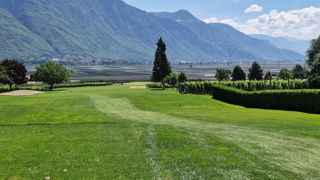 Bahn 1 des Golfplatzes Lana mit Fairway, Obstgärten und Blick ins Etschtal 